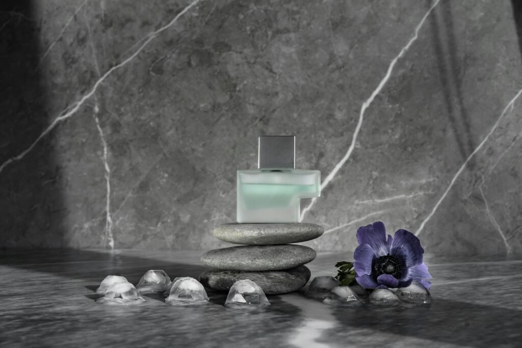 Perfume bottle displayed with stones and flower on a marble surface.